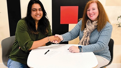 The partnership signing: a handshake across the table over the signed agreement.