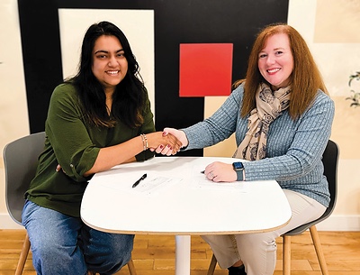 The partnership signing: a handshake across the table over the signed agreement.